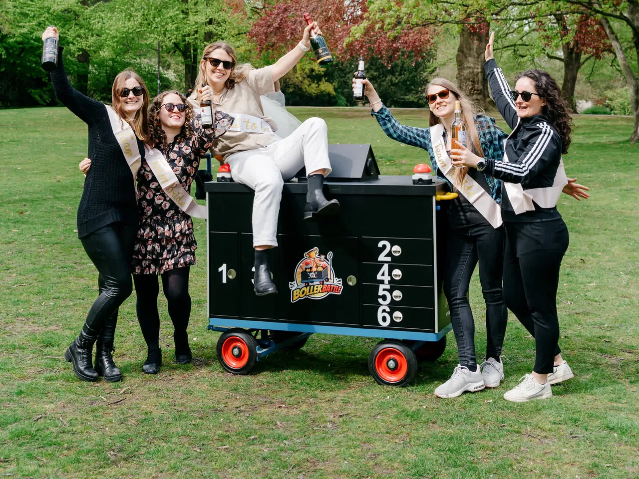 Eine JGA-Gruppe feiert mit Team-Bride-Schärpen am Battle-Wagen
